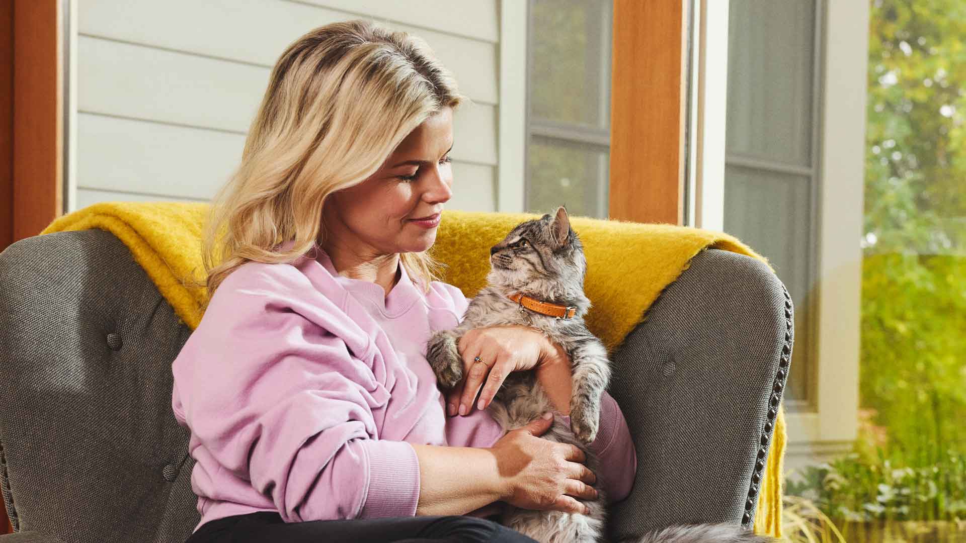 A woman sitting in a chair and holding a cat 